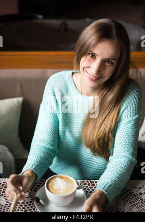 Charmante Frau in einem Restaurant. Ziemlich lächelnd kaukasische Mädchen genießen ihren Cappuccino in einem café Stockfoto