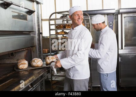 Glücklich Baker, die holding Tablett mit frischen Brötchen Stockfoto