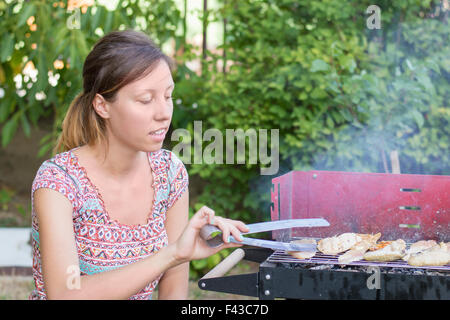 Hübsche junge Frau, die Vorbereitung der Grill im Garten Stockfoto