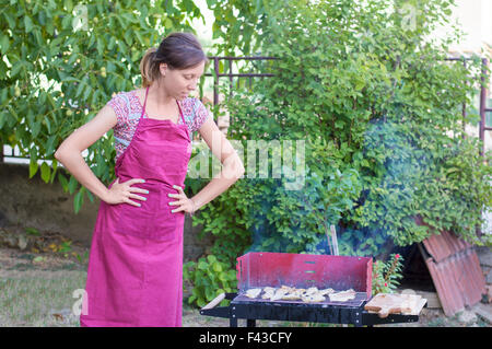 Hübsche junge Frau, die Vorbereitung der Grill im Garten Stockfoto