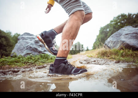 Mann im schlammigen Pfützen plantschen Stockfoto