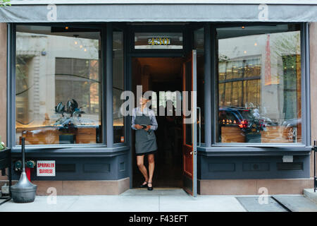 Junge Kellnerin trägt eine Schürze in einem Stadtrestaurant. Stockfoto