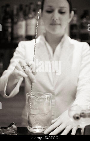 Eine junge Frau mischen einen Cocktail Mixer bei der Arbeit. Stockfoto