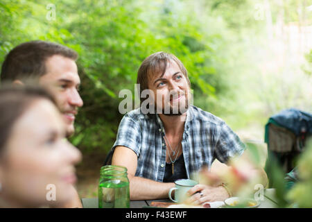 Eine Gruppe von drei Freunden draußen sitzen an einem Tisch mit einer Mahlzeit. Stockfoto