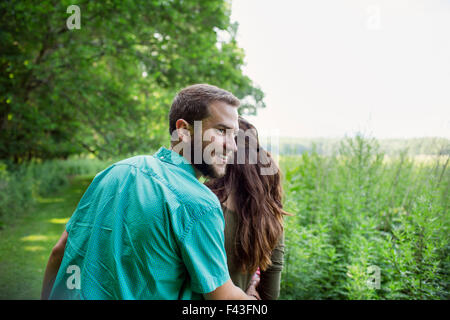 Ein Mann und eine Frau zu Fuß durch eine Wiese, das lange Gras an einem Sommertag. Stockfoto