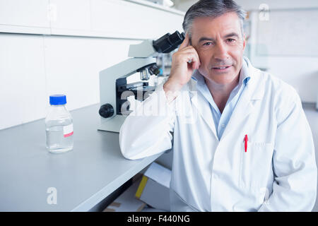 Lächelnde Wissenschaftler stützte sich auf den Tisch Stockfoto