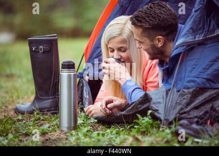 Glückliches Paar liegen im Zelt mit heißen Getränken Stockfoto