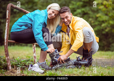 Glückliches Paar Inlineskates anziehen Stockfoto