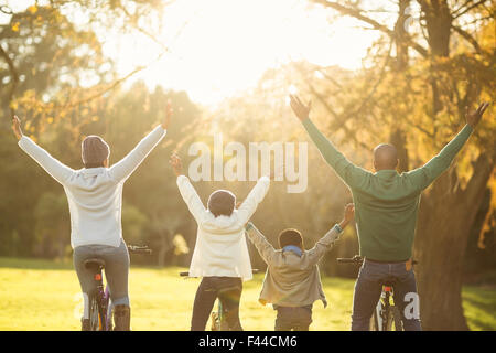 Rückansicht einer jungen Familie mit Armen angehoben auf Fahrrad Stockfoto