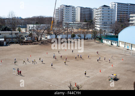 Kinder beim Spielen auf Schmutz Feld Schulhof Stockfoto