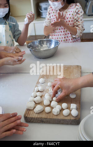 Mochi Reis die Cake Pops auf Holz schneiden Board Kinder mit Masken und Schürzen vorbereiten Stockfoto