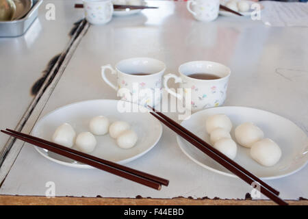 Mochi Kugeln auf beiden Platten zwei Tees und zwei Sätze von Stäbchen Stockfoto