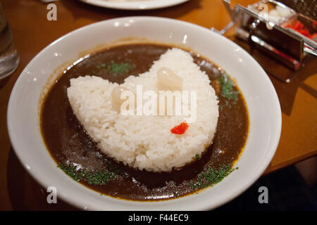 Gesicht der Katze, die mit Perlzwiebeln und Reis mit Curry auf Teller umgeben Stockfoto