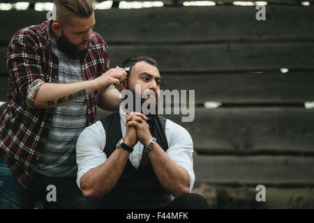 Barbier rasiert ein bärtigen Mannes Stockfoto