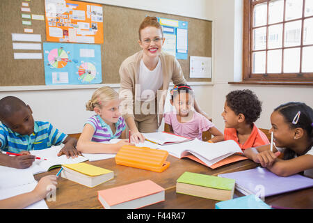 Hübsche Lehrer helfen Schülern im Klassenzimmer Stockfoto