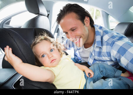 Vater sein Kind in den Kindersitz zu sichern Stockfoto