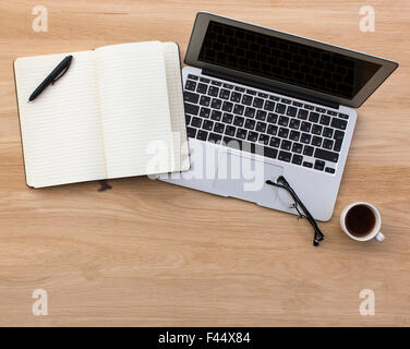 Laptop und geöffneten Notepad auf hölzernen Tischplatte anzeigen. Stockfoto