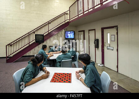 Uniformierte Hispanic teenage Insassen einer Justizanstalt für Orange, CA, spielen Dame in den Aufenthaltsraum. Beachten Sie Fernsehen. Stockfoto