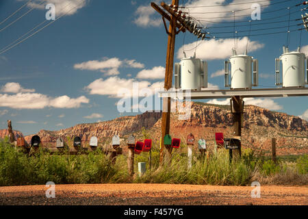 Eine Reihe von nummerierten Postfächer ist mit elektrischen Transformatoren auf einem ländlichen Lane in Cane Betten, AZ. Hinweis Butte im Hintergrund gegenübergestellt. Stockfoto