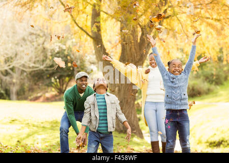 Junge Familie werfen lächelnd Blätter rund um Stockfoto