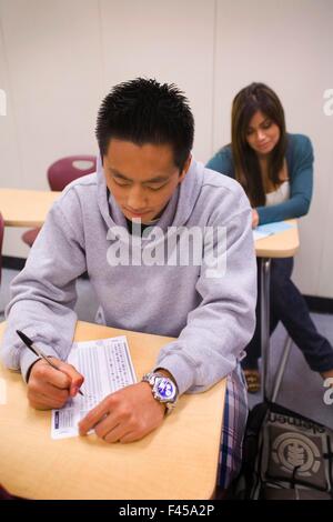 Mit Bleistift Fill Scantron Blättern, nehmen multirassische Southern California Community College-Studenten einen standardisierten Test auf maschinenlesbaren Papierformularen Kennzeichnung Antworten auf Multiple-Choice-Test-Fragen. Optische Markierung Anerkennung und imaging-Scanner sind Stockfoto