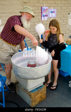 Eine Mädchen glücklich Tween serviert Zuckerwatte von einem bärtigen Freiwilligen in einer Gemeinschaft Handwerk Messe in Mission Viejo, Kalifornien. Stockfoto