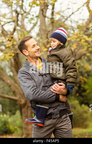 Junger Vater Aufhebung seines kleinen Sohnes im park Stockfoto