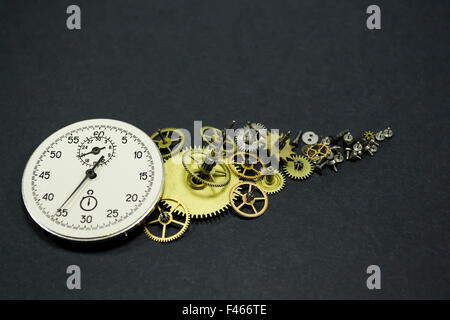 Stoppuhr Zifferblatt mit Uhr Mechanismus gezahnte Räder und Kleinteile auf schwarzem Hintergrund, Konzeptbild über Zeit Stockfoto