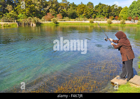 Verschleierte Frau Angeln am See Garten Stockfoto