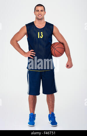 In voller Länge Portrait von ein hübscher Basketball-Spieler stehen isoliert auf einem weißen Hintergrund und einen Blick auf Kamera Stockfoto