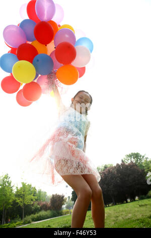 Mädchen halten Haufen Luftballons Stockfoto