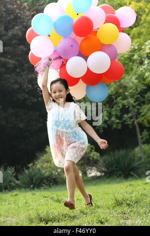 Mädchen halten Haufen Luftballons Stockfoto