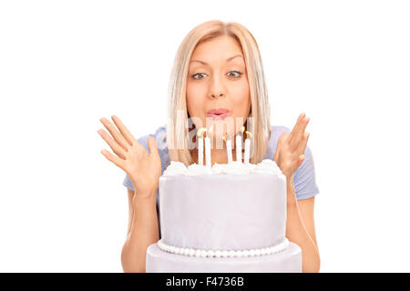 Studioaufnahme einer überglücklich blonde Frau bläst Kerzen auf einem Geburtstag Kuchen isoliert auf weißem Hintergrund Stockfoto