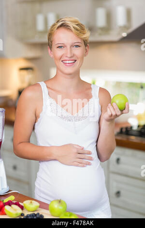 Schwangere Frau, die einen grünen Apfel zu essen Stockfoto