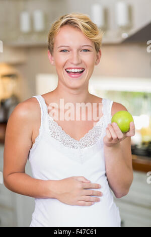Schwangere Frau, die einen grünen Apfel zu essen Stockfoto