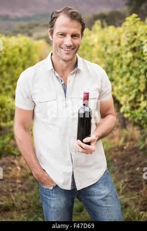 Lächelnd mit einer Flasche Rotwein Winzer Stockfoto