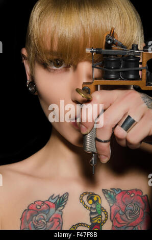 tätowierte schöne Frau mit Tattoomaschine Stockfoto