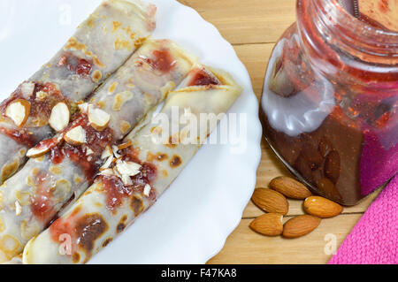 Süße Pfannkuchen mit Erdbeer Konfitüre und Haselnüsse auf den Teller serviert Stockfoto