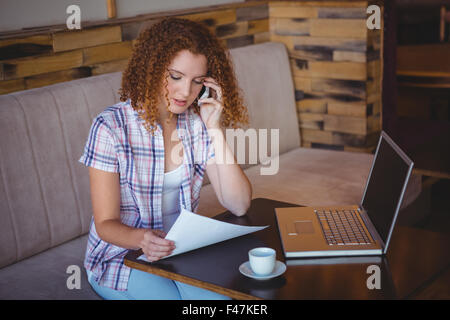 Gerne hübsche Frau telefonieren und mit ihrem laptop Stockfoto