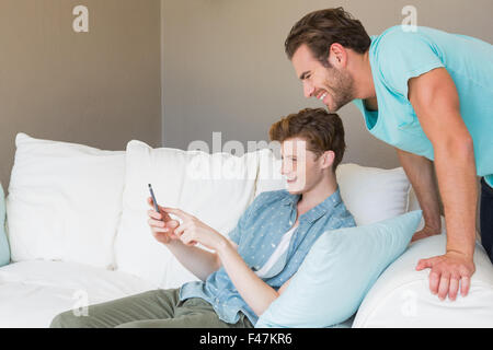 Glückliche homosexuelle Paar Smartphone betrachten Stockfoto