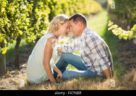 Paar sitzt eng mit Augen geschlossen neben Weinrebe Stockfoto