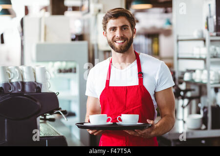 Gut aussehend Barista hält zwei Tassen Kaffee Stockfoto