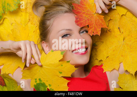 junge Frau in gelb Herbst Ahorn Blätter Stockfoto