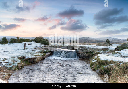 Eine idyllische Winterlandschaft mit Schnee auf dem Boden und einem wunderschönen Wasserfall, auf Dartmoor National Park in Devon Stockfoto