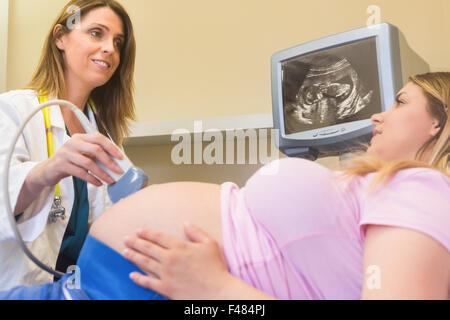 Lächelnde Arzt zeigt Ultraschalluntersuchung für ihre Patienten Stockfoto