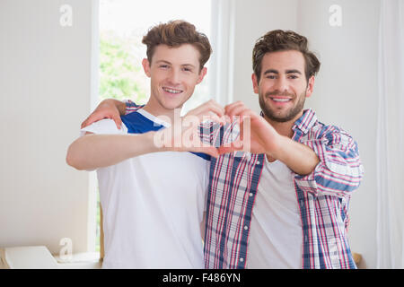 Homosexuelles Paar glücklich lächelnd in die Kamera und die Herzform mit Händen Stockfoto