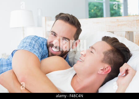 Glückliche homosexuelle Paar auf Bett liegend Stockfoto