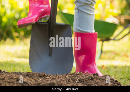 Frau Rosa Gummi Stiefel mit Schaufel Stockfoto