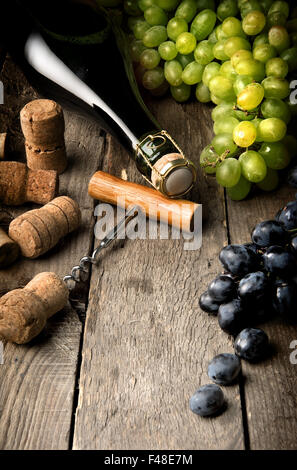 Wein mit Trauben und Korken auf Holztisch Stockfoto