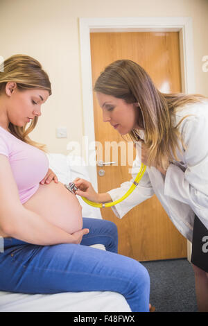 Junger Arzt überprüft ihre schwangeren Patientin Stockfoto